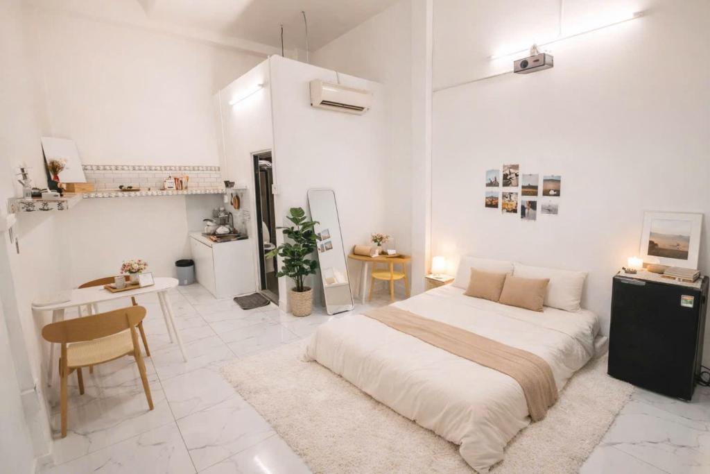 a white bedroom with a bed and a table at December homestay studio 002 in Ho Chi Minh City