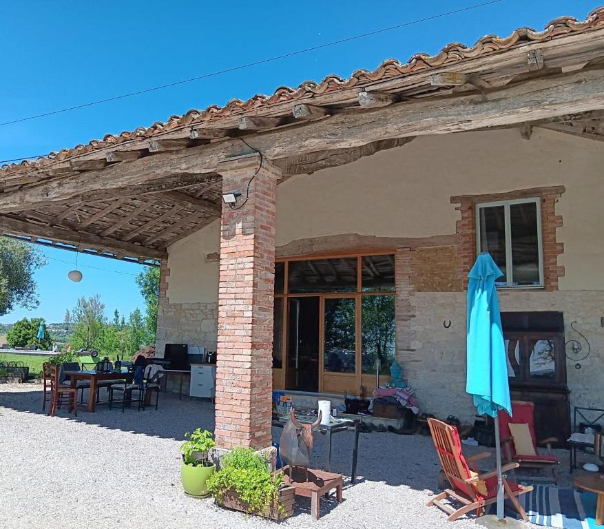 a building with a patio with chairs and an umbrella at Escale Zen en Quercy in Montalzat