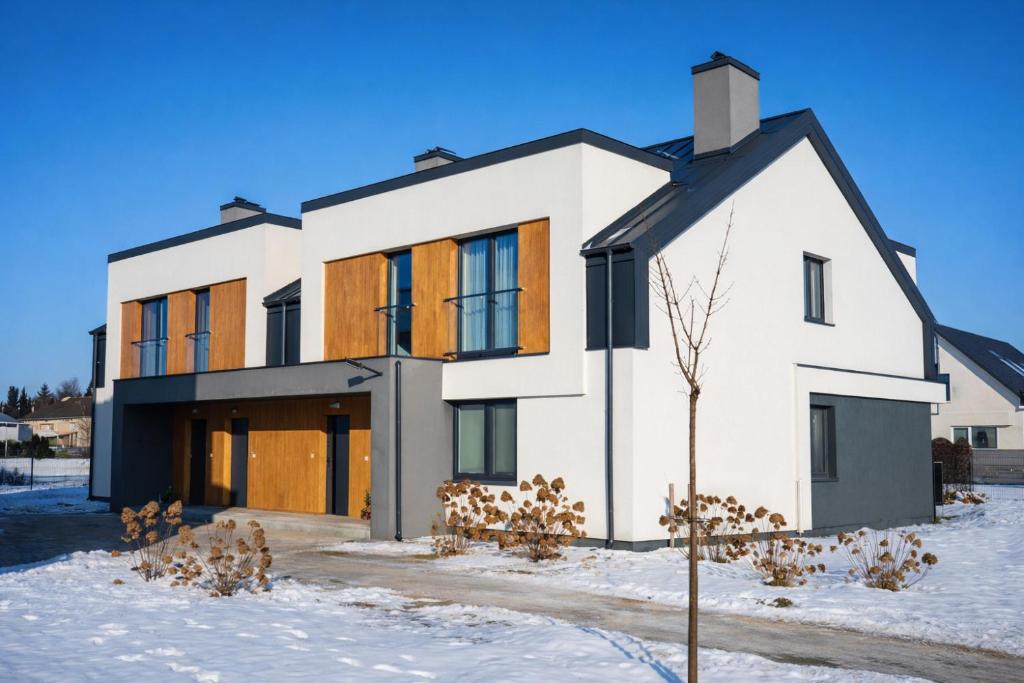 a white house with a black roof in the snow at Modern 2023 apartment in Kutno