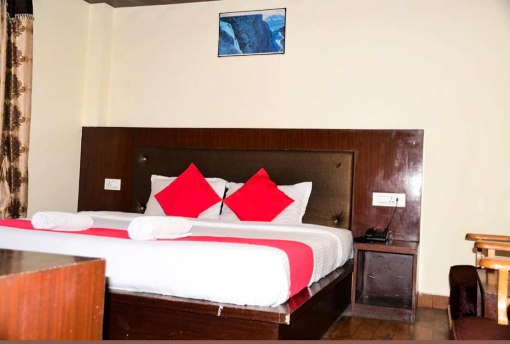a bedroom with a large bed with red pillows at Hotel tridev in Manāli