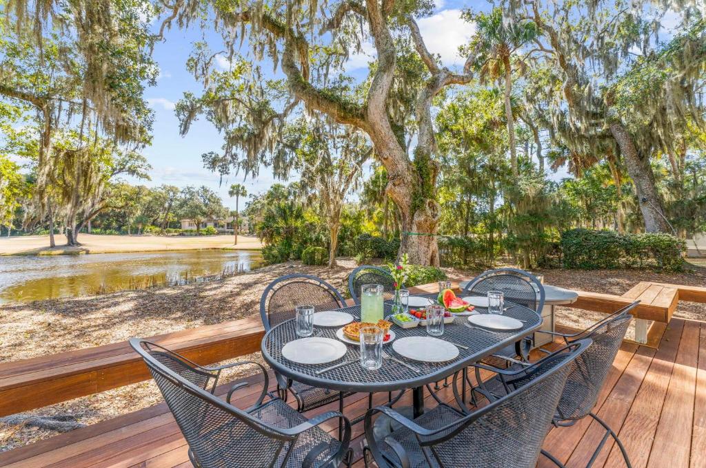 a table with chairs on a wooden deck with trees at 2455 The Bent Twig in Seabrook Island