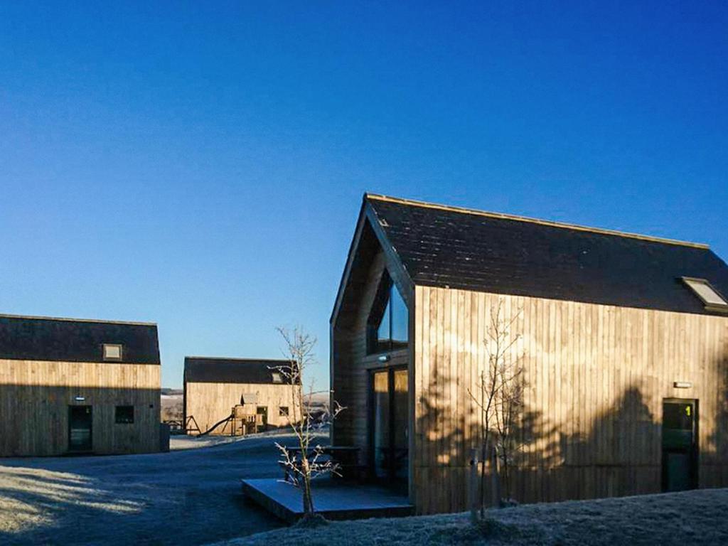 a wooden barn with a building in a field at Jupiter 1 - Uk50471 in Greenhaugh