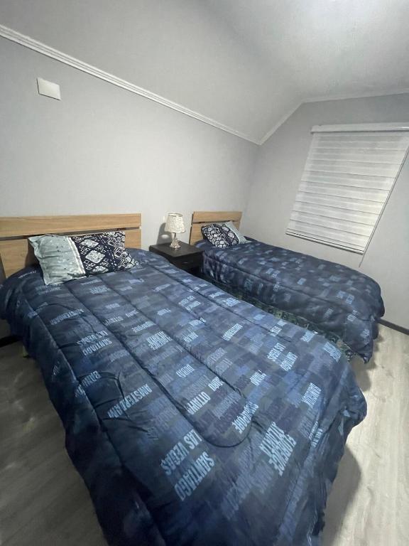 a bedroom with two beds and a window at departamento central in Valdivia