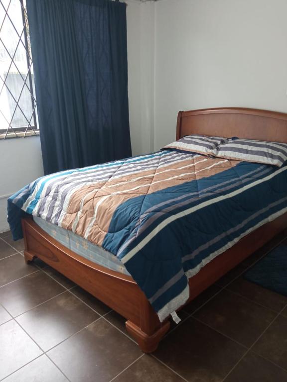 a bedroom with a bed with a blue and brown comforter at SUITE CUMBAYA Junto Reservorio in Quito