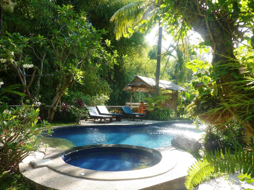une piscine au milieu d'un jardin avec un banc dans l'établissement Saraswati Holiday House, à Lovina