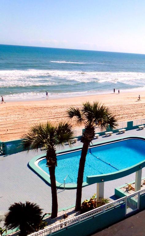 a view of a beach with palm trees and a swimming pool at Chateau Mar Beach Hotel NEWLY REFURBISHED in Ormond Beach