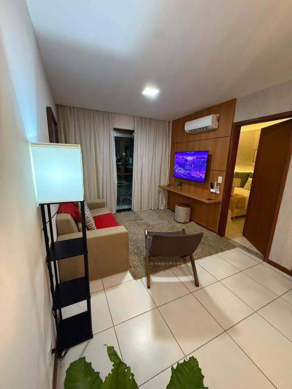 a living room with a couch and a tv at Apartamento em Resort para família in Barra de São Miguel