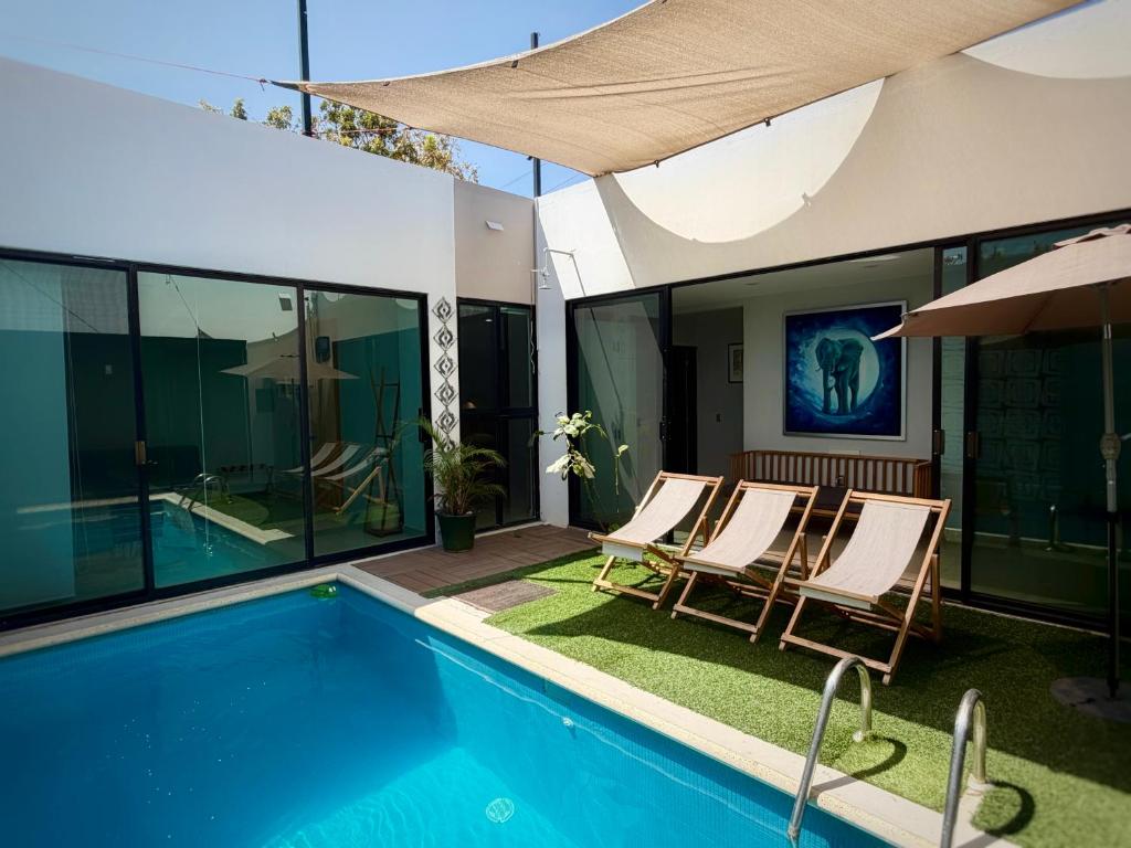 a house with a swimming pool with chairs and an umbrella at "Casa Mosso" en San Felipe del Agua in Oaxaca City