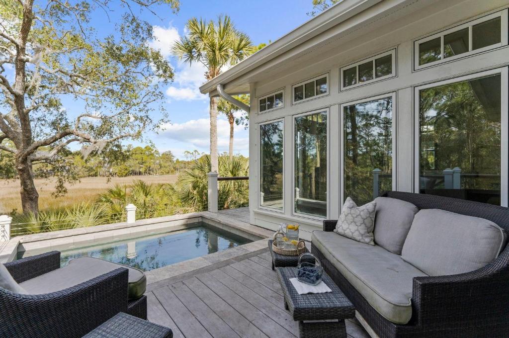 a patio with a couch and chairs next to a pool at 711 Glossy Ibis in Kiawah Island