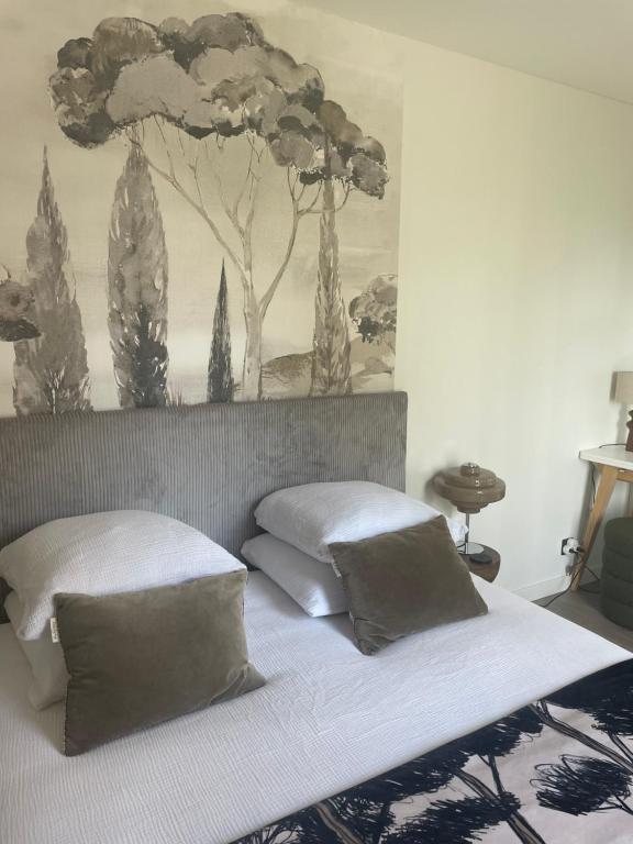 a bed with two pillows and a painting on the wall at L'Escale d'Omaha - Cottage de 50m2 in Saint-Marcouf