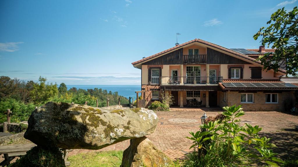 a house with a large rock in front of it at Igeldo in Orio