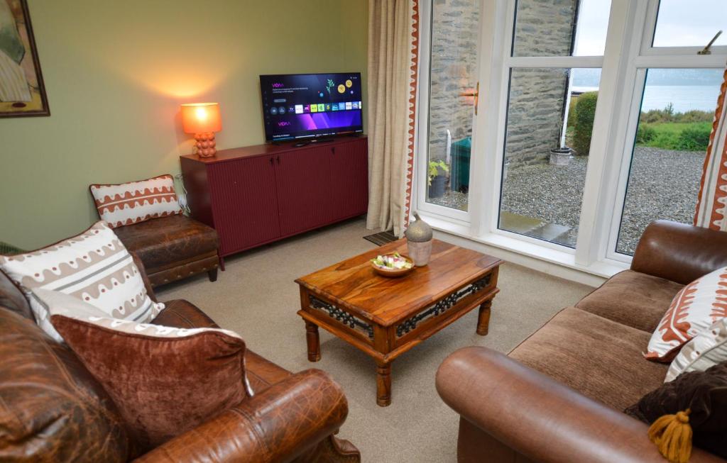 a living room with leather furniture and a tv at Dunmore Coastal Retreat in Dunoon