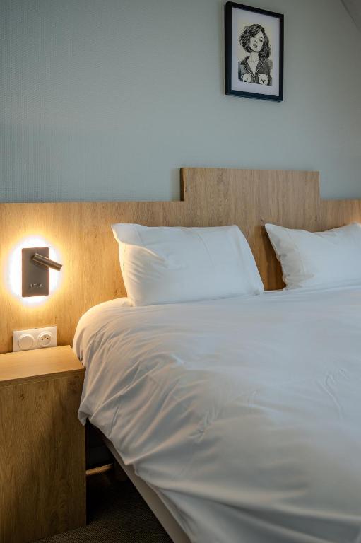a bedroom with a large white bed and a night stand at Tulip Inn Honfleur Residence & Spa in Honfleur