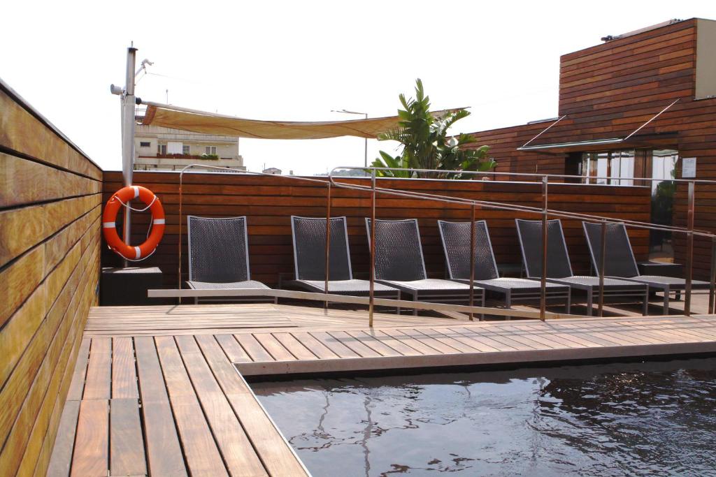a group of chairs sitting on a deck next to a pool at Hotel Soho in Barcelona