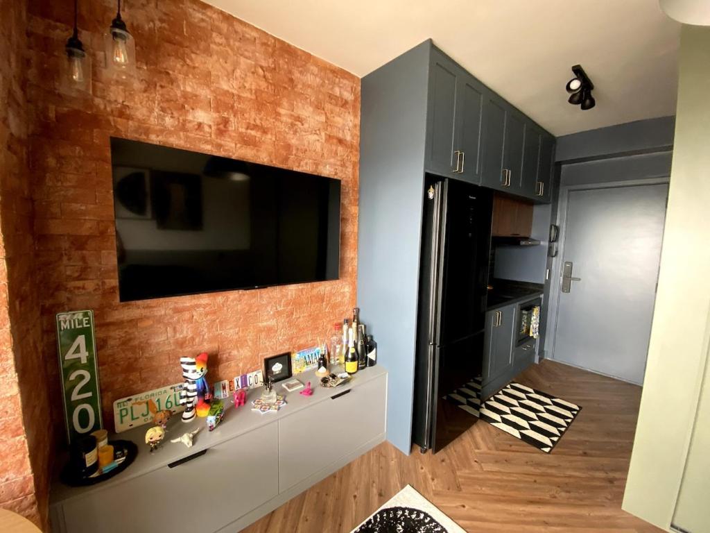 a living room with a television on a brick wall at Central Studio in the metro Butantã in São Paulo