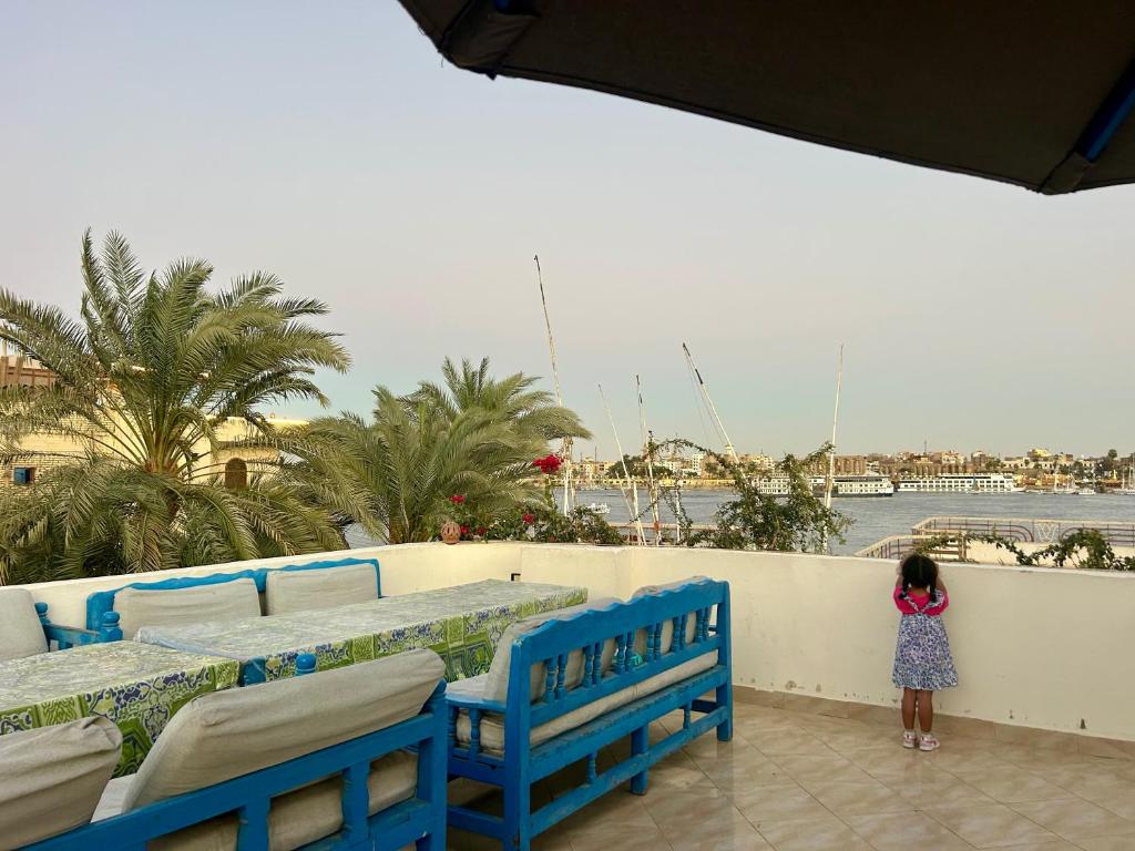 a little girl standing next to two blue benches at Gîte Hôtel Ramla Louxor in Luxor