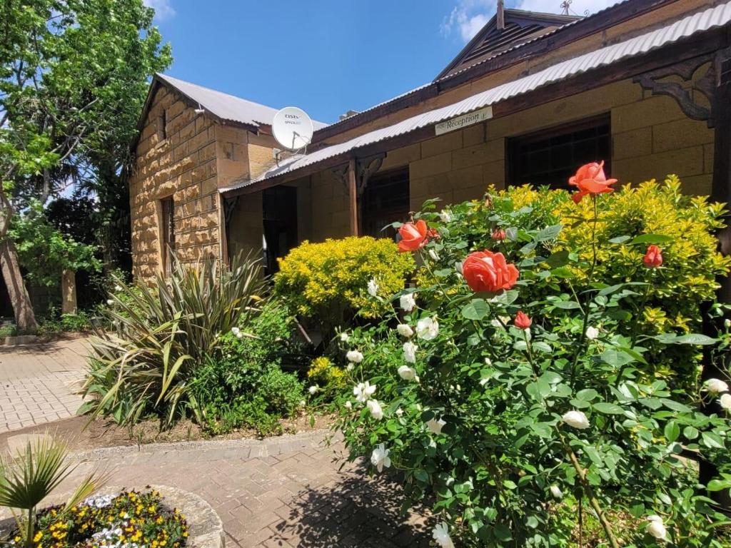a garden of flowers in front of a house at Sandstone Escape Guesthouse in Ladybrand