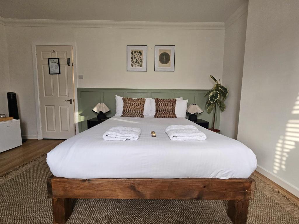 a bedroom with a large bed with two towels on it at Saint Margaret's Guest House - Comfortable Rooms in a Quiet Area Close to the Heart of Poole - Free Parking & Fast Wifi in Poole