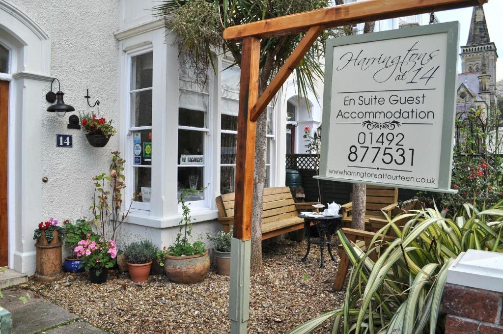 a sign in front of a building with a bench at Harringtons at 14 in Llandudno