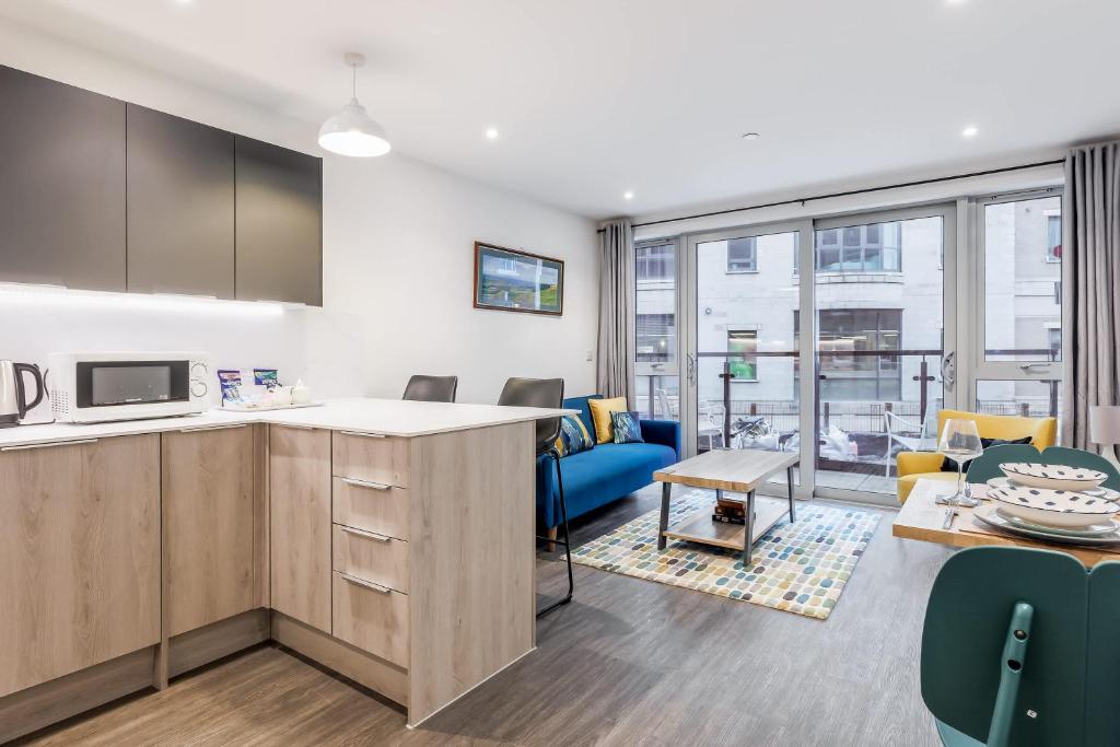 an open kitchen and living room with a couch and chairs at Once Upon a Tide - Stylish Apartment in the Heart of Poole in Poole