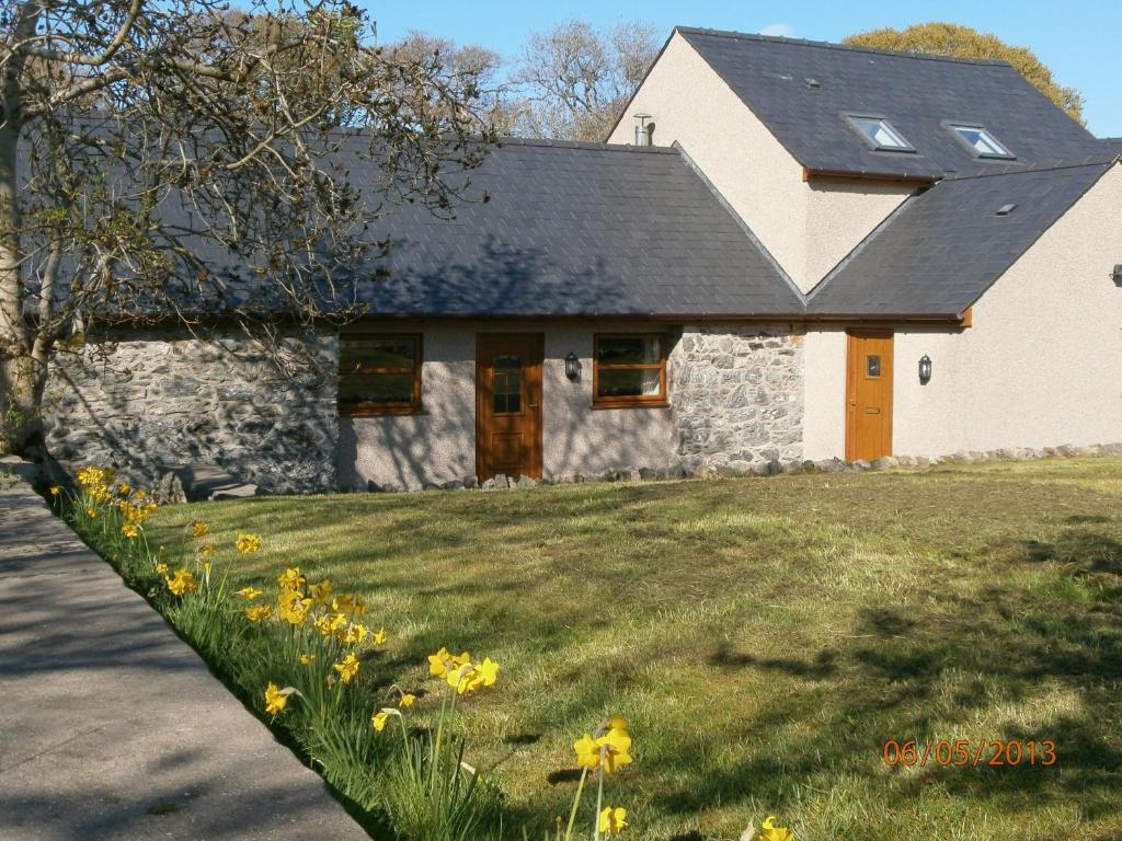 a stone house with yellow flowers in front of it at Fodol Cottages in Menai Bridge