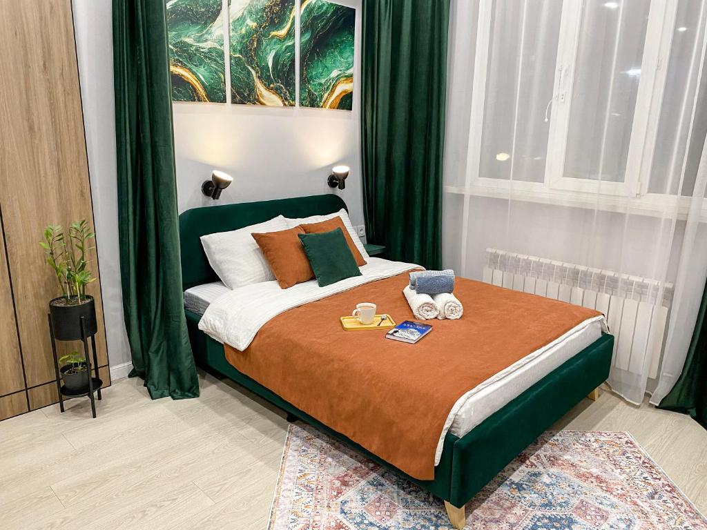 a bedroom with a large bed with green curtains at Contento Apartments in Almaty