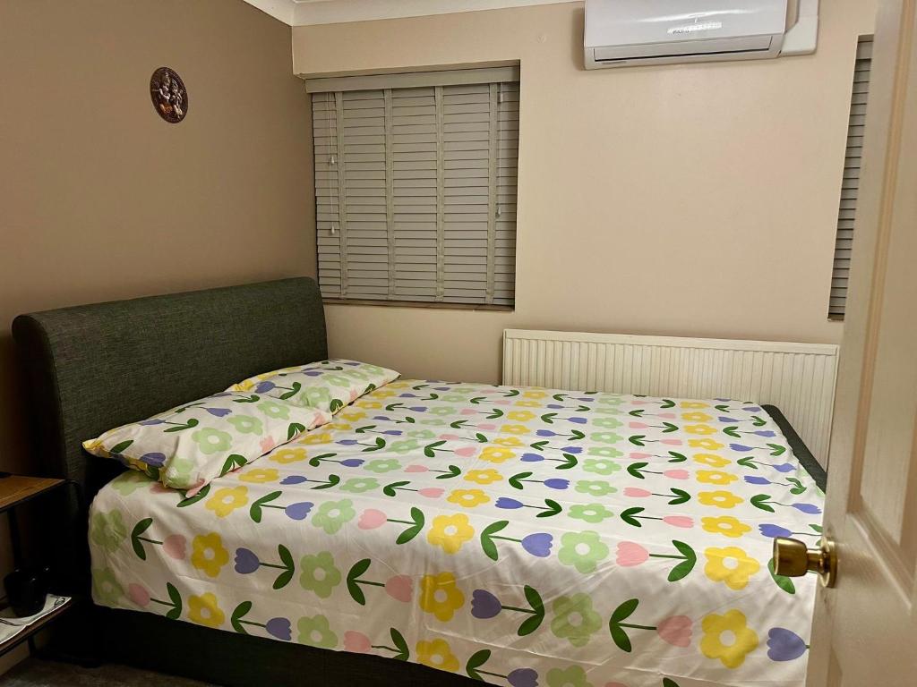 a bedroom with a bed with a flower comforter at Comfy En-suite room in Gloucester