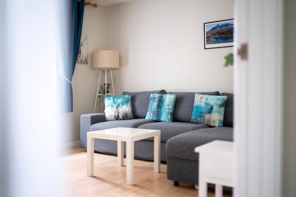 a living room with a blue couch and a table at Lombard Hide Away in Inverness