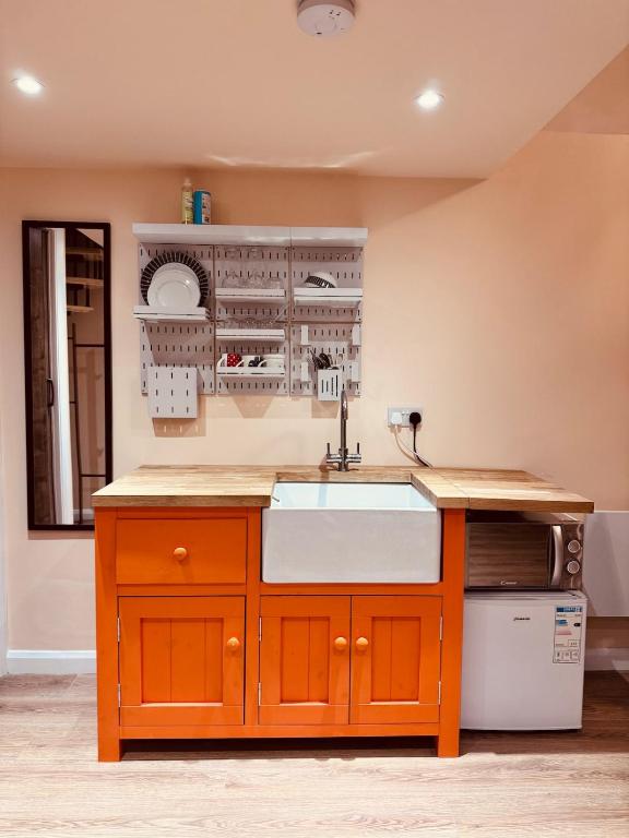 a kitchen with an orange cabinet and a sink at Golden Oak Guest House in North Leigh