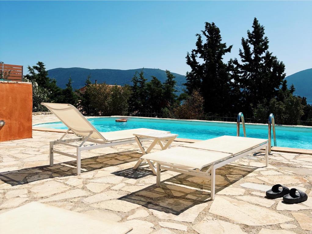 a pair of chairs and a table next to a swimming pool at Sea View Villa Irene - Private Pool and Sunset Terrace in Evretí