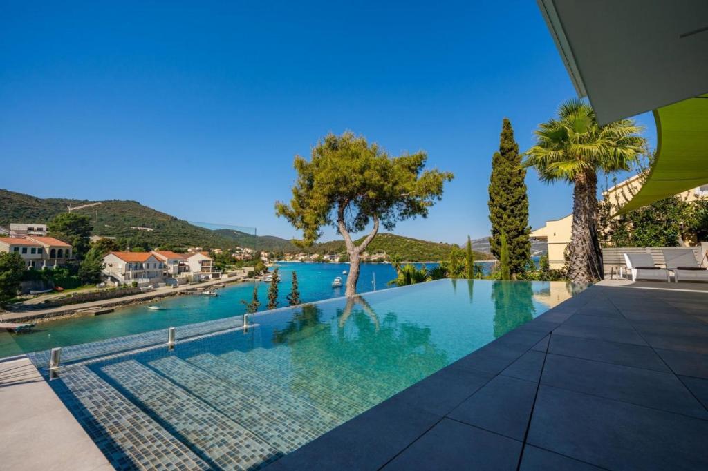 a swimming pool in a villa with palm trees at Luxury Seafront Villa Aman Korcula with Pool in Korčula