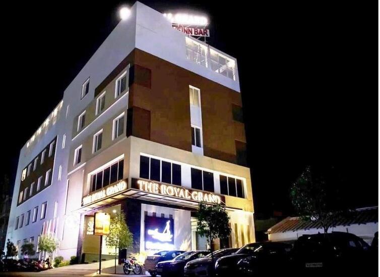 a building with cars parked in front of it at night at The Royal Grand in Karūr