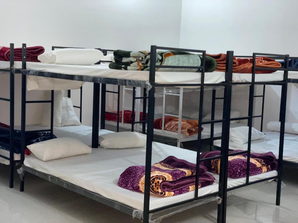 a group of three bunk beds with towels and blankets at The rest point dormitory in Khātu