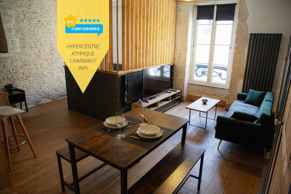 a living room with a table and a tv at Le Millésime in Dijon
