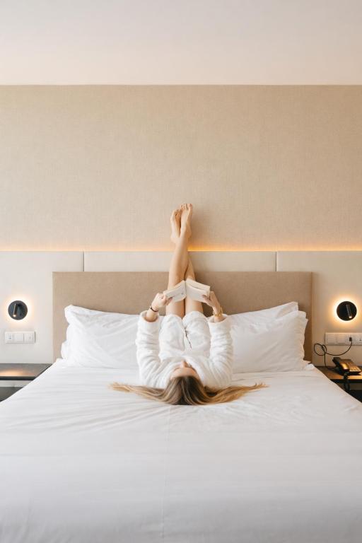 a woman laying on a bed with her legs in the air at Oporto Fly Hotel in Maia