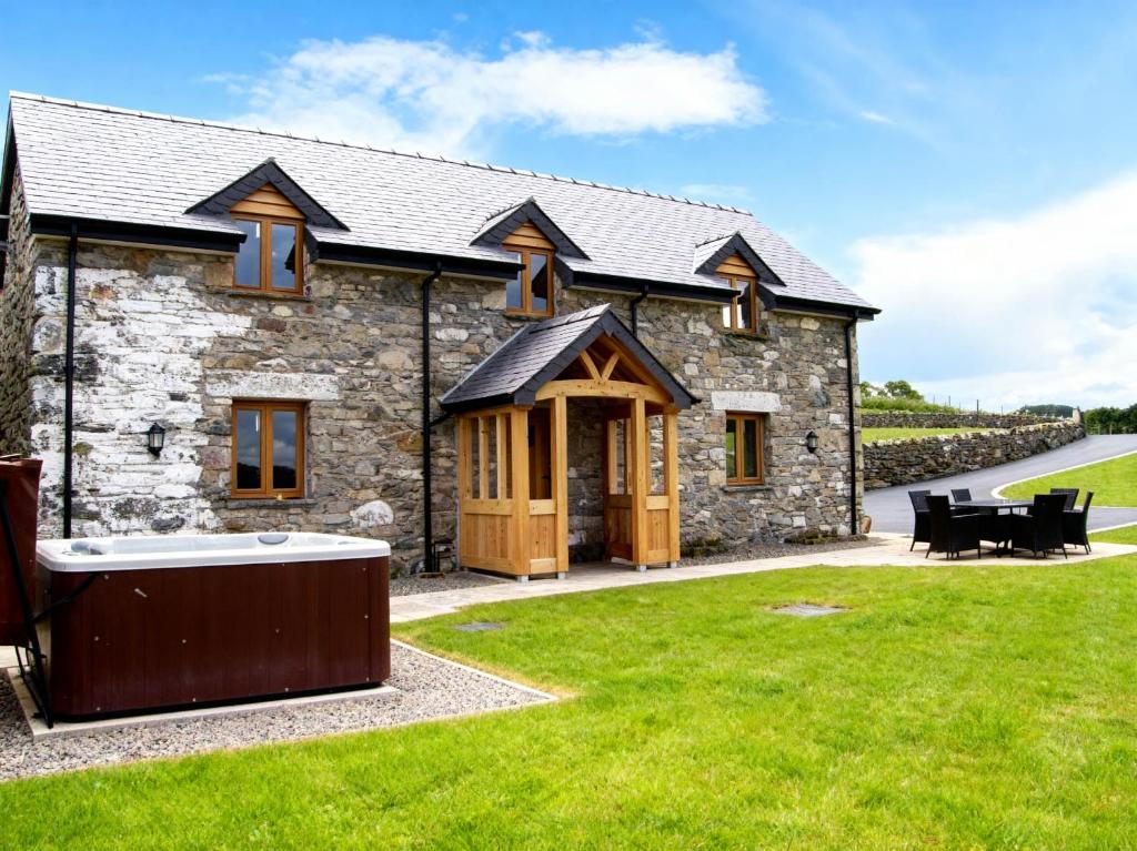 a stone house with a hot tub in the yard at Tyn Y Celyn Canol in Clocaenog