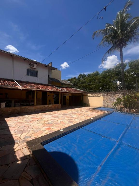a swimming pool in front of a house with a palm tree at Pousada Gaivota in Trindade