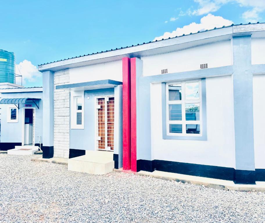 a white building with red trim on a street at Fusion Apartments in Lusaka