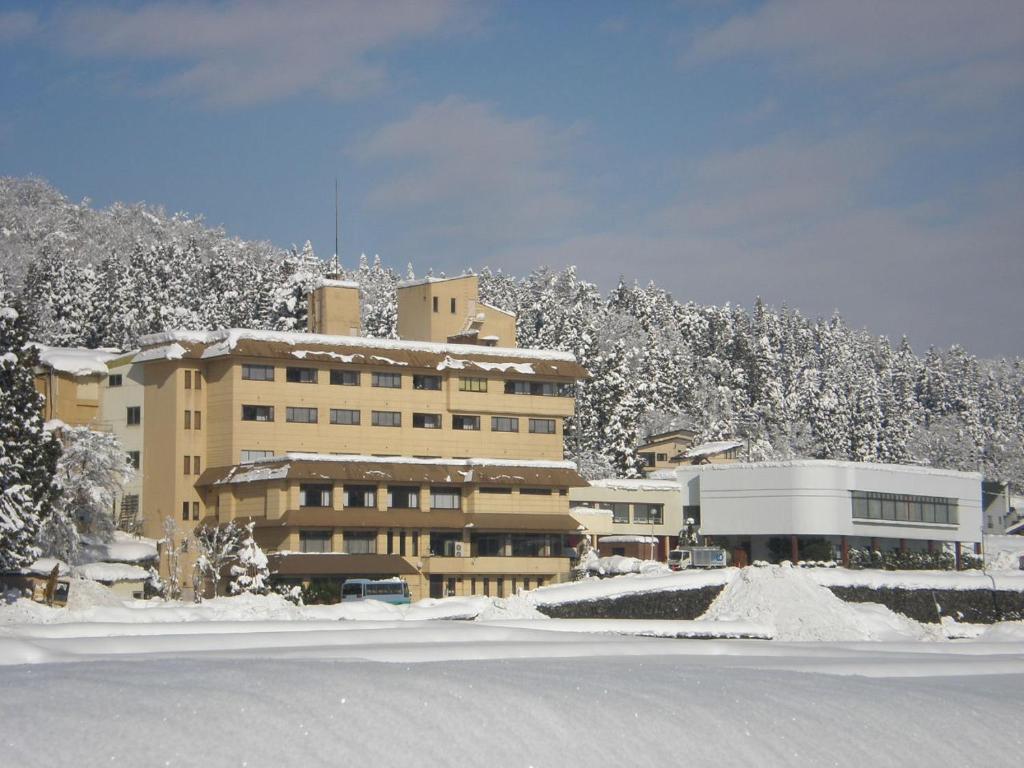 a large building with snow covered trees in front of it at Hotel Kinomezaka in Minami Uonuma