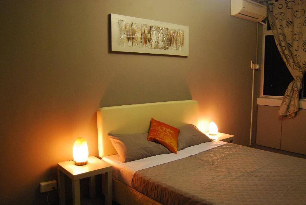 Un dormitorio con una cama con dos luces. en Borneo Sweet Guesthouse en Kuching