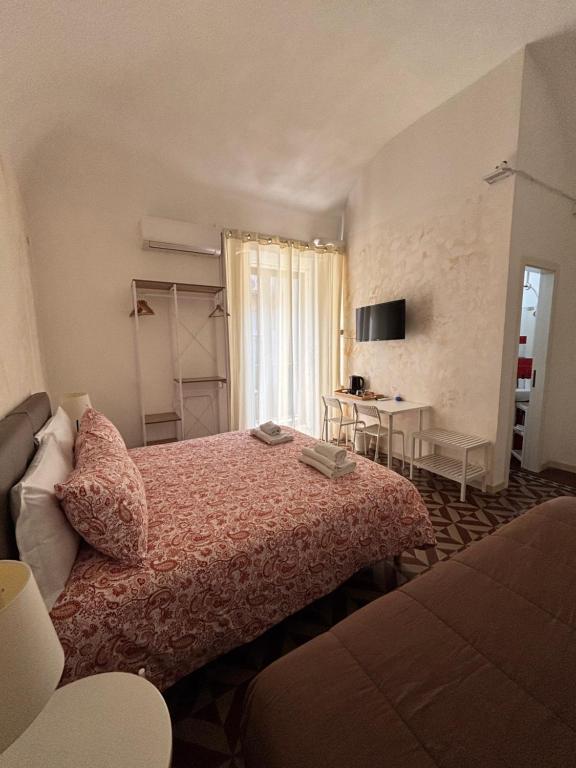 a bedroom with a bed and a table and a window at Il Teatro Rooms in Catania