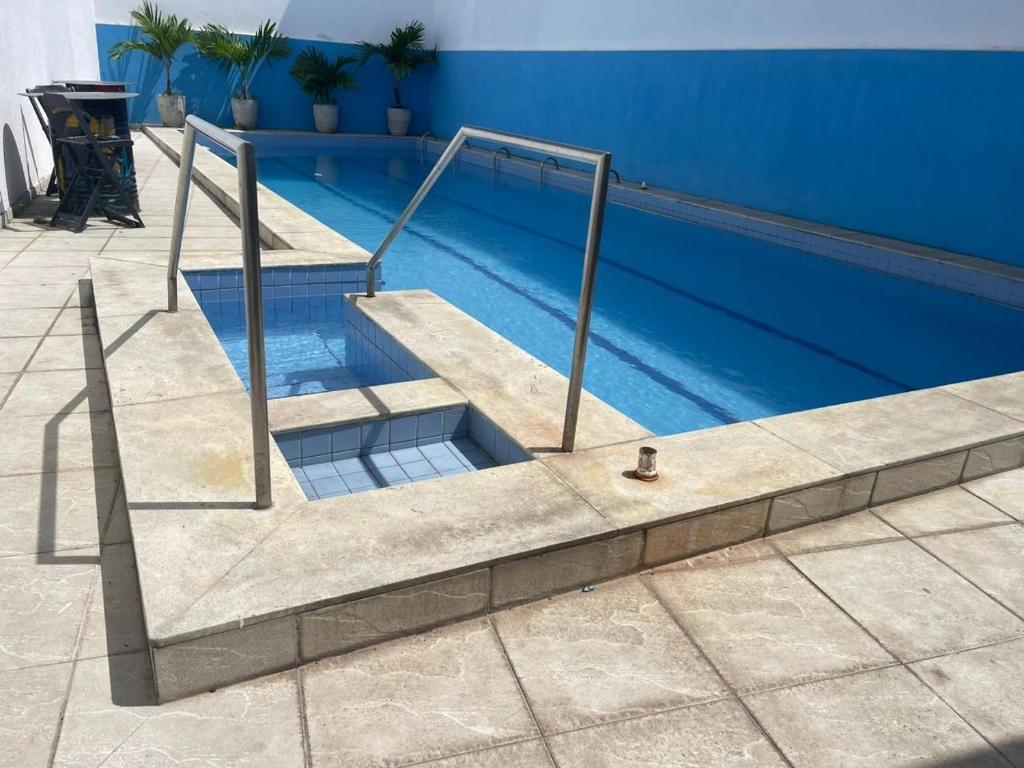 a swimming pool with stairs next to a blue wall at Pousada Maré Alta in Maceió