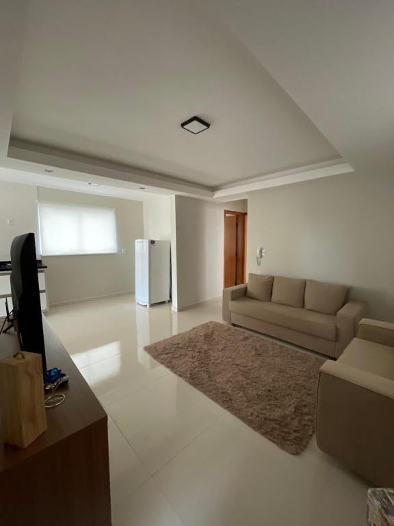 a living room with a couch and a television at Apartamento em Poços - Varanda com Churrasqueira in Poços de Caldas