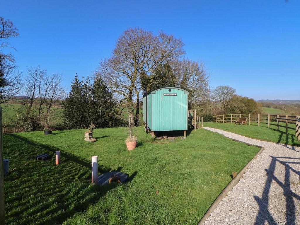 a green shed sitting in the grass in a field at Shepherds Delight in Macclesfield