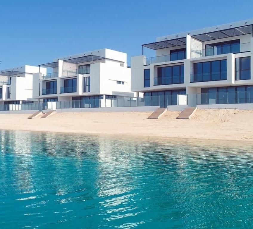 ein Gebäude direkt am Wasser mit einem Strand in der Unterkunft Beachfront Villa with Heated Private Pool & Jacuzzi in Al Ḩamrīyah