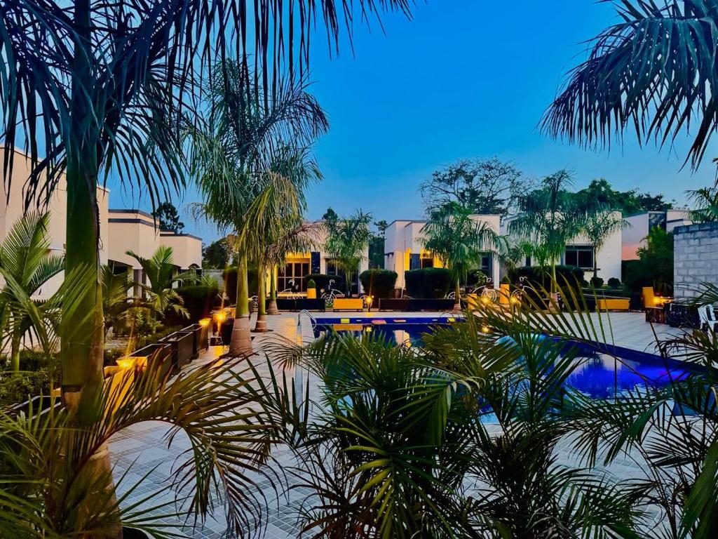 a resort with a pool and palm trees and buildings at Pieme Hotel Residence in Migade