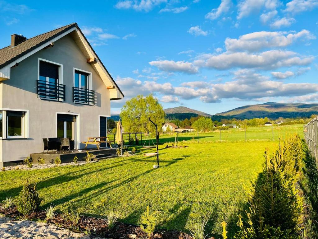 a house with a green field and mountains in the background at Polny Domek in Bystrzyca Kłodzka