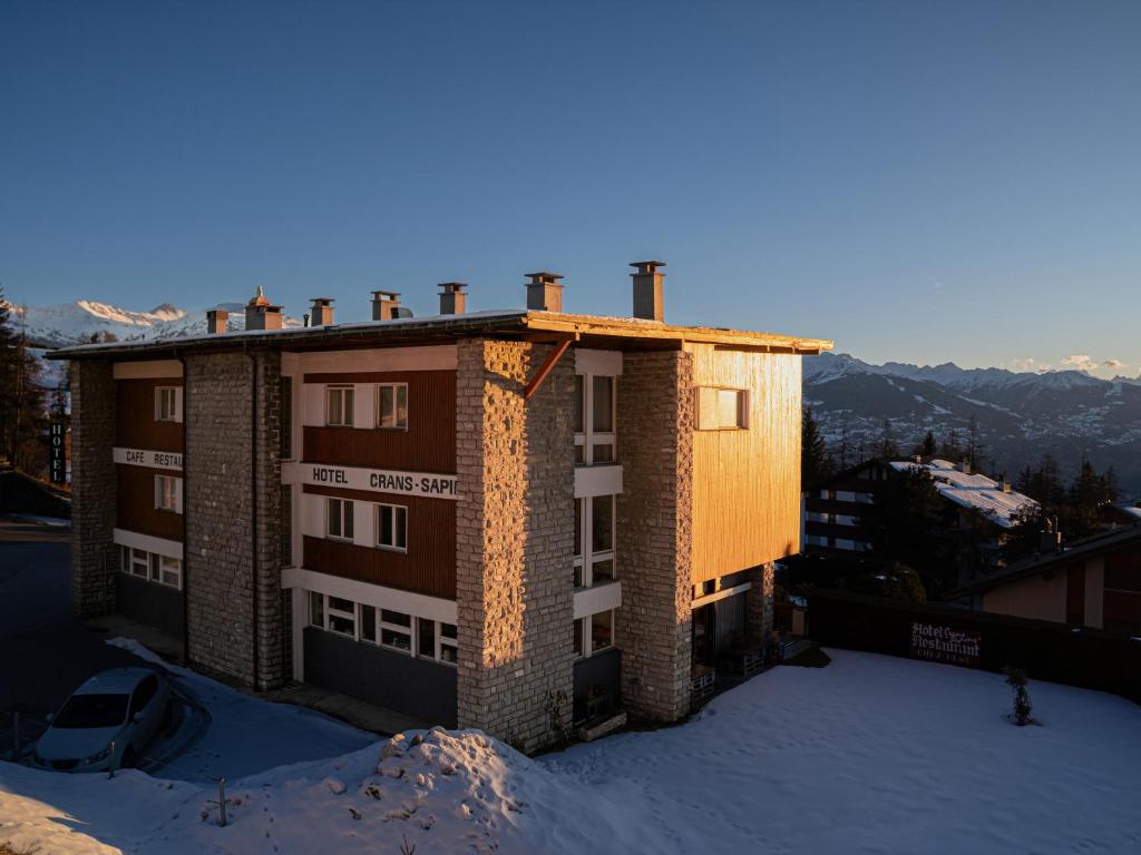 a building with snow on the ground in front of it at Hôtel historique Chez Elsy - Crans-Sapins in Crans-Montana