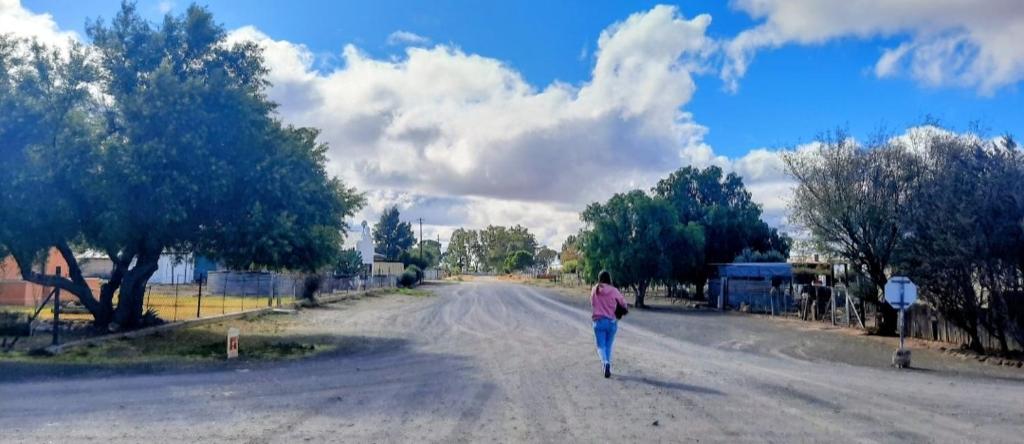 a woman walking down a road in the street at Ebenezer Verblyf in Fraserburg