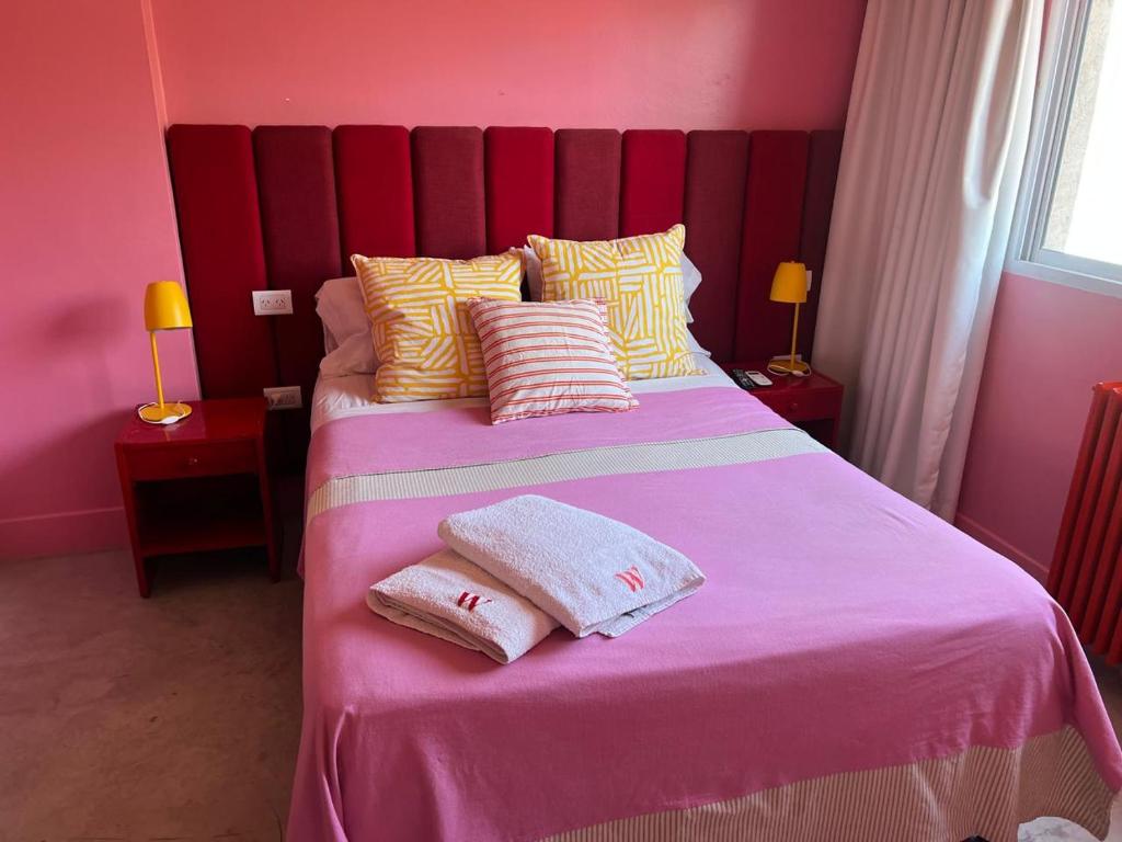 a pink bedroom with a bed with two towels on it at Hotel Windsor Mendoza in Mendoza